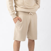Person wearing beige shorts and a matching hoodie on a white background