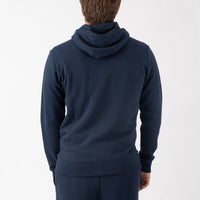 Person wearing a navy blue hoodie and pants on a white background