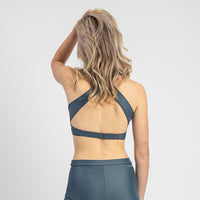 Woman wearing a gray sports bra and leggings on a white background