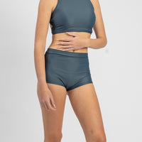 Person wearing a matching teal sports bra and shorts set on a white background