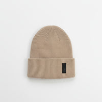 Beige knit beanie with a black label on a light gray background