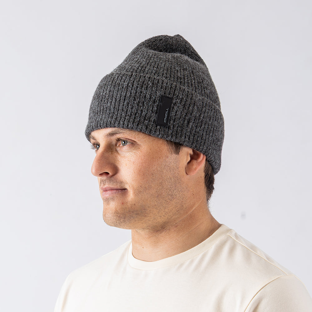 Man wearing a gray knit beanie with a logo on a white background